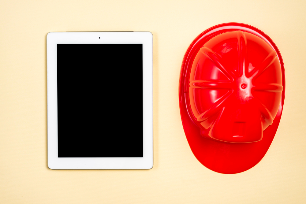 Conheça todas as cores de capacetes de obras e das fábricas 9 construction helmet near digital tablet with blank screen display beige background